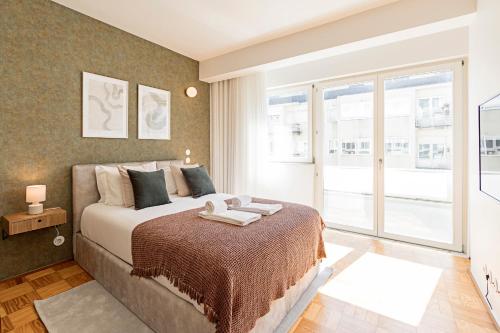 een slaapkamer met een bed en een groot raam bij Ceuta Studio Apartments by LovelyStay in Porto