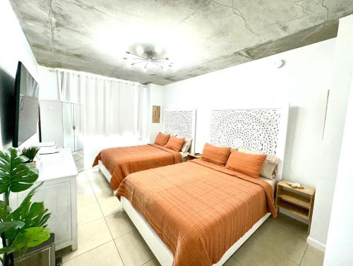 Duas camas num pequeno quarto com lençóis laranja em Platinum 1BD 1BTH at Midblock em Miami