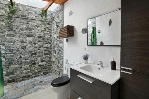 baño con lavabo blanco y pared de piedra en Casa Rural Jovial, en Ingenio