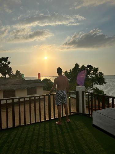 a man standing on a balcony looking at the sunset at MKS - Kite & Wing Foil camp in Kalpitiya