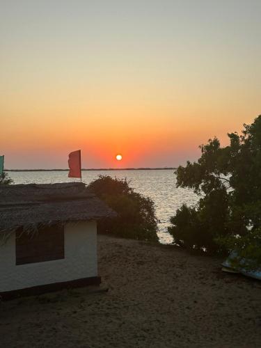 a house on the beach with the sunset in the background at MKS - Kite & Wing Foil camp in Kalpitiya