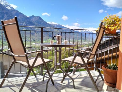 a table and chairs on a balcony with mountains at La casetta del sole in Quart