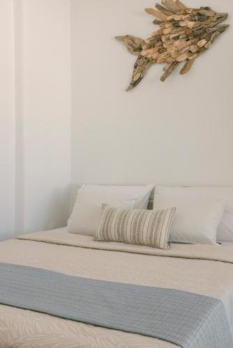 a bed with white sheets and a bird on the wall at Pebble Summer House in Kampos Paros