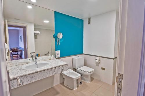 W łazience znajduje się umywalka, toaleta i lustro. w obiekcie Coral La Quinta Park Suites w mieście Santa Úrsula