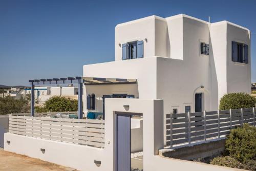 a white house with a fence in front of it at Pebble Summer House in Kampos Paros