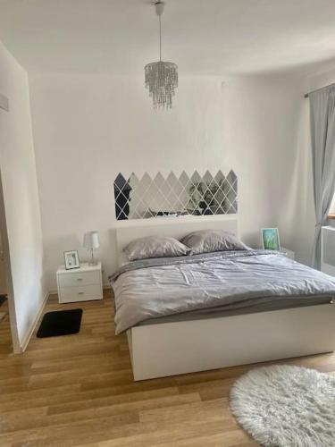 a white bedroom with a bed and a wooden floor at Zuzanittin rozpravkový domček in Rožňava