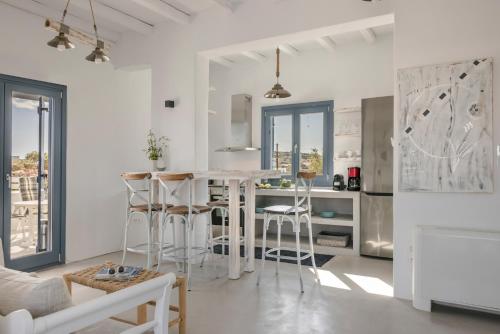 a white kitchen with a bar with stools at Pebble Summer House in Kampos Paros