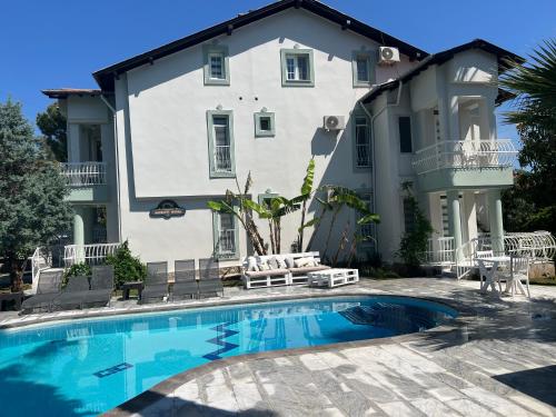 a house with a swimming pool in front of a building at Göcek Selya Hotel in Göcek