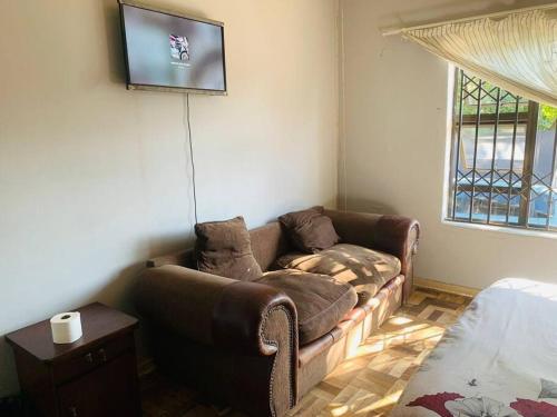 ein Wohnzimmer mit einem Sofa und einem TV an der Wand in der Unterkunft Slumber Lake Guest House in Roodepoort