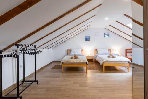 GračacにあるSOKOL - Secret forest houseの白い壁とウッドフロアの屋根裏部屋のベッド2台