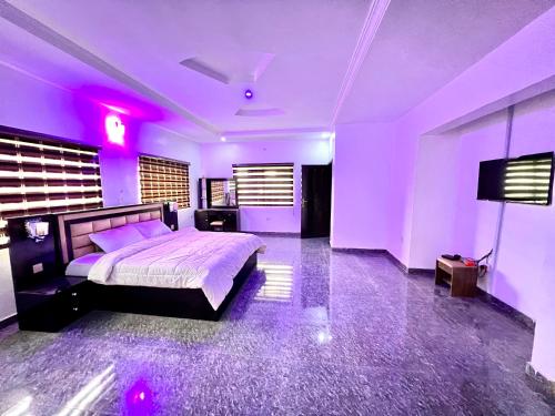 CampDavid Luxury Apartments Ajao Estate Airport Road Lagos 0 8 1 4 0 0 1 3 1 2 5 في لاغوس: غرفة نوم بسرير كبير مع اضاءة ارجوانية