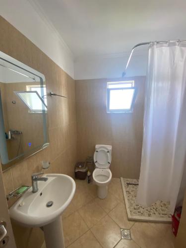 een badkamer met een wastafel, een toilet en een spiegel bij Saranda relax apartments in Sarandë
