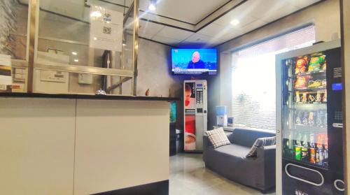 a living room with a refrigerator and a couch and a television at Hôtel Moderne in Saint-Denis