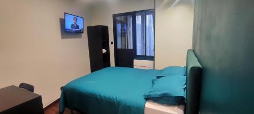 a bedroom with a blue bed and a television at Hôtel Moderne in Saint-Denis