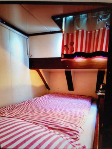 Etagenbett mit einer roten und weißen gestreiften Decke in der Unterkunft Schiff AHOY, Hotelschiff, Hausboot, Boot, Passagierschiff in Stuttgart