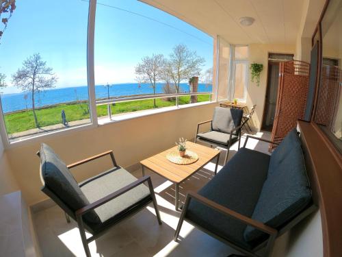 Sala de estar con sillas y mesa y vistas al océano en Sunset Yavorov Pomorie, en Pomorie