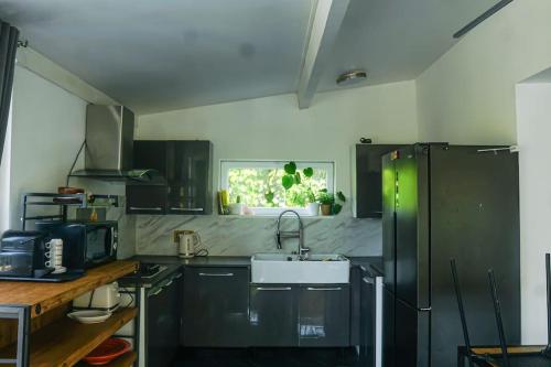 d'une cuisine avec des placards noirs, un évier et une fenêtre. dans l'établissement RIVA BELLA villa plage, à Bandol