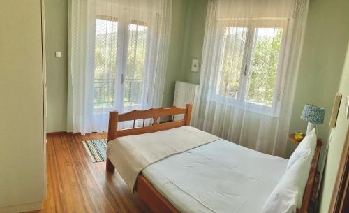 a bedroom with a bed and two windows at Carpenter's House in Skala Sotiros