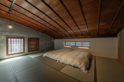 a large bed in a room with a wooden ceiling at Hitoiki in Nagahama