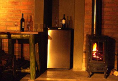 a fireplace in a room with a refrigerator and a stove at Hotel Rustico Cerro Del Valle in San Agustín de Valle Fértil