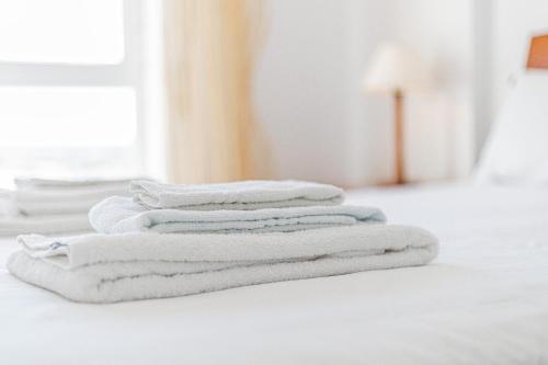 アルマカオ・デ・ペラにあるShinning View Apartmentの白いタオルの積み重ねがベッドに座っている