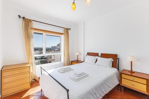 Schlafzimmer mit einem weißen Bett und einem Fenster in der Unterkunft Shinning View Apartment in Armação de Pêra