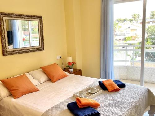 a bedroom with a bed with a mirror and a window at APARTBEACH LARIMAR MUY LUMINOSO y CLIMATIZADO in Salou