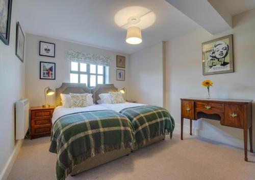 a bedroom with a bed and a desk and a window at 3 Hilltop Cottages in Stansted