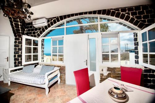 Cette chambre dispose d'une grande fenêtre, d'une table et de chaises. dans l'établissement Dawn Suites Santorini, à Vourvoúlos