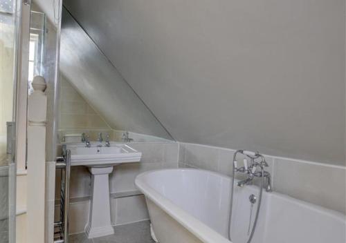 a white bathroom with a tub and a sink at 3 Stable Mews in Royal Tunbridge Wells