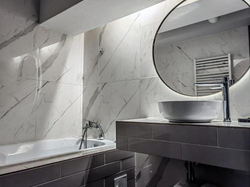 een badkamer met een wastafel, een spiegel en een bad bij JN Boutique House in Boekarest