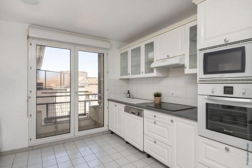 une cuisine avec des placards blancs et une grande fenêtre dans l'établissement NOCNOC - Le Pargamin - Large duplex Place Saint-Pierre, à Toulouse