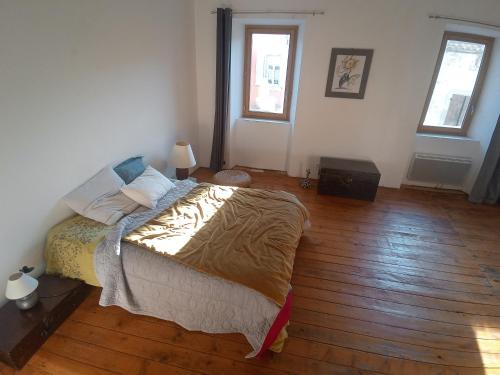 une chambre avec un lit et un parquet dans l'établissement Maison de village, à Bourdeaux