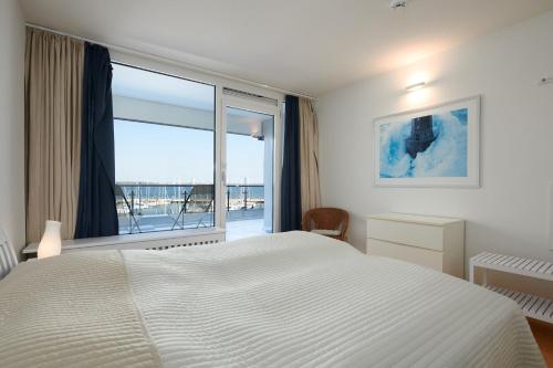 a bedroom with a white bed and a large window at BRN Bootsmann in Laboe