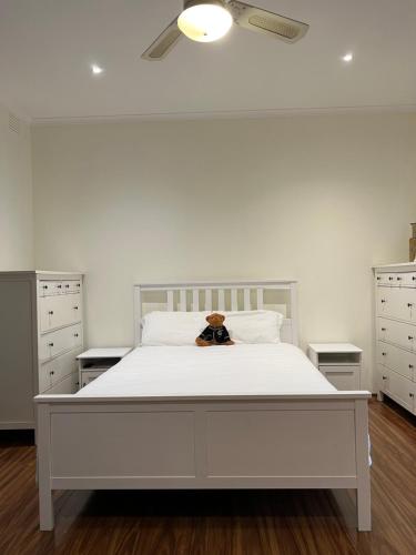 a bedroom with a white bed with a teddy bear on it at Beautiful Parkview Luxury Four 4 Bedrooms House in Doncaster East