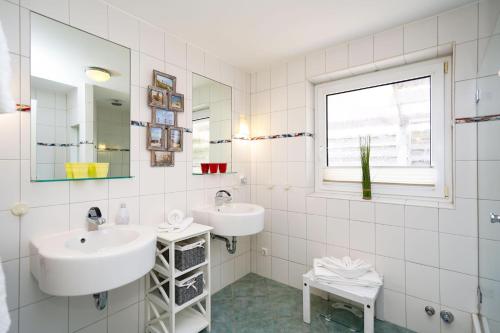 Baño blanco con 2 lavabos y ventana en Silwai EG, en Tinnum