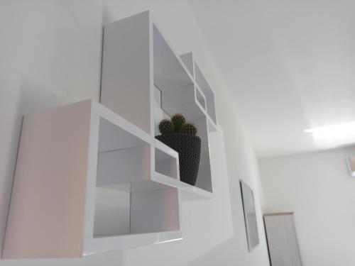 a white wall with a potted plant on a shelf at Venite Rooms in Velika