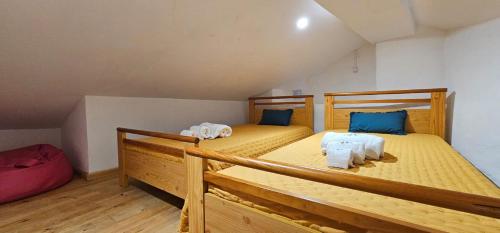 2 Betten in einem Zimmer mit gelber Bettwäsche und blauen Kissen in der Unterkunft CASA DO AVÔ FILIPE 