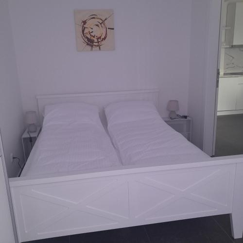 a white bed in a white bedroom with white sheets at Spa Koncept-Apartmani in Veliko Gradište