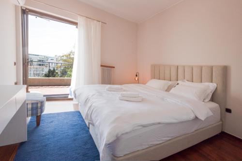 una camera da letto con un grande letto bianco con una grande finestra di Seaside Apartment with 3 bdrm and Shared Pool! ad Atene