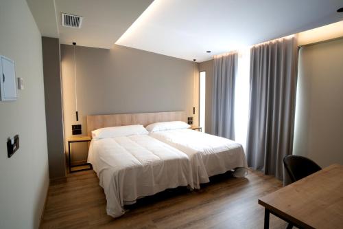 um quarto com uma cama branca e uma mesa em HOTEL RIO LEA 