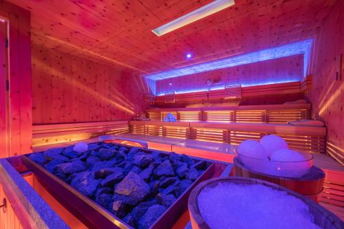 a sauna with a tub filled with lots of rocks at Garni Appartements Almrausch in Burgusio