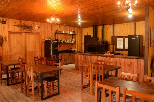 a restaurant with wooden tables and chairs and a kitchen at Pousada Querência Tarumã in São Joaquim