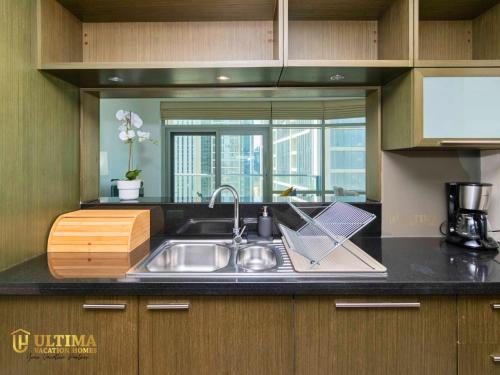 Ultima Vacation Homes loft 1 BR Apartment في دبي: طاولة مطبخ مع حوض ونافذة
