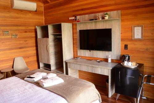 a bedroom with a bed and a desk and a television at Pousada Querência Tarumã in São Joaquim