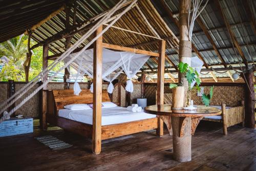 a bedroom with a canopy bed and a table at Secret Villa in La Digue