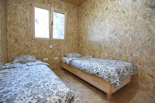 two twin beds in a room with a window at TreeHouses Ljubač Glamping Robinson in Ljubač