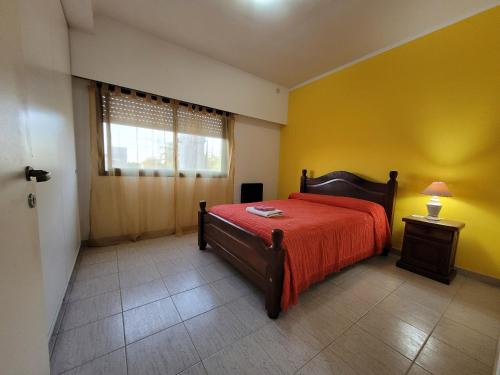 a bedroom with a bed with a red blanket and a window at "La Irma" - Complejo de Departamentos in Lincoln