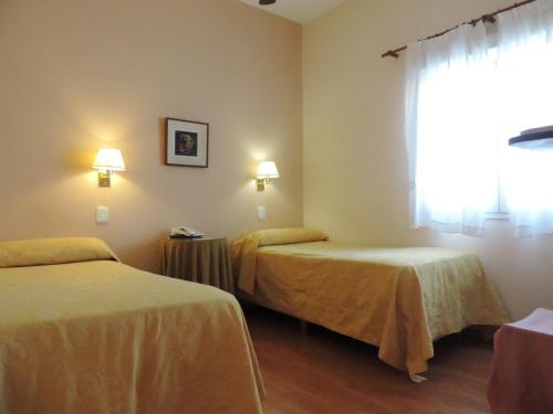 een hotelkamer met 2 bedden en een raam bij Hotel Galicia in Trelew