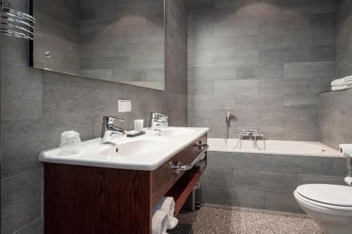 a bathroom with a sink and a toilet and a tub at Leerhotel Het Klooster in Amersfoort